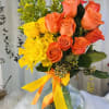 Bouquet of orange and yellow roses in a glass vase with ribbon