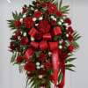 Tall red and white funeral spray on an easel with roses, daisies, and a red 'Beloved' ribbon