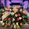 Large casket spray of pink, peach, and white roses with ribbons reading Loving Mom and Loving Nana.