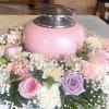 Pink urn surrounded by pastel roses and white filler flowers