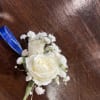 White rose boutonniere with baby's breath and blue ribbon