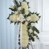 White floral cross on an easel with ribbon