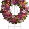 Heart-shaped floral wreath on a white easel with pink, purple, and yellow flowers