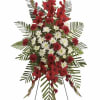 Standing floral spray with red gladiolus and white daisies on a metal easel