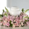 Pink roses and carnations arranged around a white urn