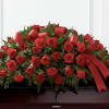 Red roses and carnations arranged with red ribbon on a casket