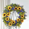 Sunflower wreath with blue and yellow flowers on a black stand
