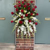 Tall standing floral spray with red roses and white orchids on a metal easel