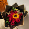 Bouquet of red roses and a sunflower in black wrapping with gold butterfly accents