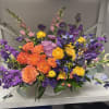 Colorful mixed bouquet in a white vase with purple, orange, and yellow blooms