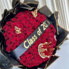 Large bouquet of red roses wrapped in black paper with gold butterflies, crown, and Class of 2023 banner