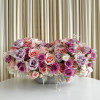 Low centerpiece of pink, lavender, and white roses in a gray bowl on a white table