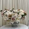 Low centerpiece of ivory and blush roses and white blooms in a stone compote vase on a round table