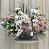 Large pastel floral arrangement with white orchids and blush roses in a black vase