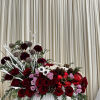 Large red and pink floral arrangement in a white vase