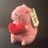 Pink plush alpaca holding a red heart with a hanging gift tag