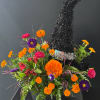 Bright orange, pink, and purple flowers arranged around a black tinsel tree centerpiece.