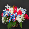 Basket of red, white, and blue flowers with star decorations and ribbon