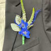 Blue boutonniere with white spikes pinned to a black suit jacket