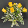 Yellow roses arranged in a clear vase with baby's breath and a yellow ribbon.