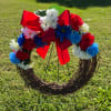 Floral wreath with red, white, and blue flowers and a large red bow