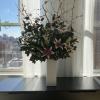 Tall floral arrangement with pink lilies and flowering branches in a white pedestal vase