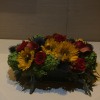 Low floral centerpiece with sunflowers, red roses, and calla lilies
