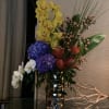 Tall mixed floral arrangement in a metallic vase with orchids and hydrangeas