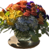 Colorful bouquet with yellow calla lilies, orange roses, blue hydrangea, and purple accents in a glass vase