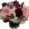 Bouquet of pink gerbera daisies, red roses, and white hydrangeas in a glass vase