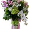 Pink lilies and white orchids in a pink-wrapped vase arrangement