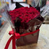 Bouquet of red roses wrapped in dark paper with a red ribbon