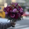 Handheld bouquet of purple and red flowers with a wrapped stem