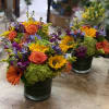 Bright mixed flower arrangements in dark glass vases