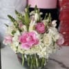 Pink and white flowers arranged in a clear glass vase