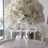 White floral arrangement in a clear glass vase with trailing orchids