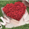 Heart-shaped box filled with red roses and pale pink ribbon