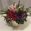 Mixed bouquet of red roses, pink lilies, and purple ornamental cabbage in a vase