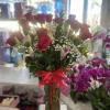 Tall bouquet of red roses and white lilies in a glass vase with a red ribbon