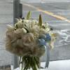 White bouquet in a clear glass vase with a blue ribbon