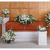 White funeral flowers arranged around a casket