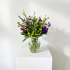 Purple and green mixed bouquet in a clear glass vase