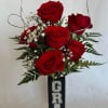 Red roses arranged in a tall black vase with a GRAD sign