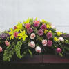 Casket spray with pink and purple roses and yellow lilies