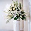 White lilies and cream roses arranged in a tall white vase