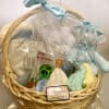 Gift basket with baby clothes, plush toys, and a teether