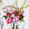 Pink lilies and roses in a glass vase with a ribbon
