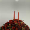 Red floral centerpiece with two tall candles and pinecones