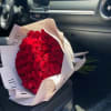 Bouquet of red roses wrapped in white paper on a car seat