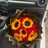 Bouquet of red roses and yellow sunflowers wrapped in dark paper